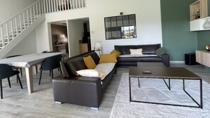 Un salon moderne avec un canapé, une table basse et un escalier menant à un niveau supérieur.