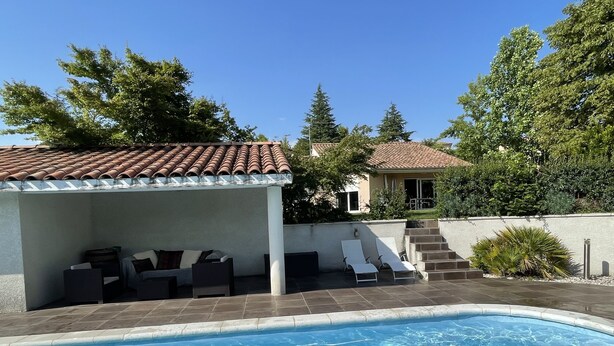 Une piscine avec des chaises longues et un espace de repos abrité.