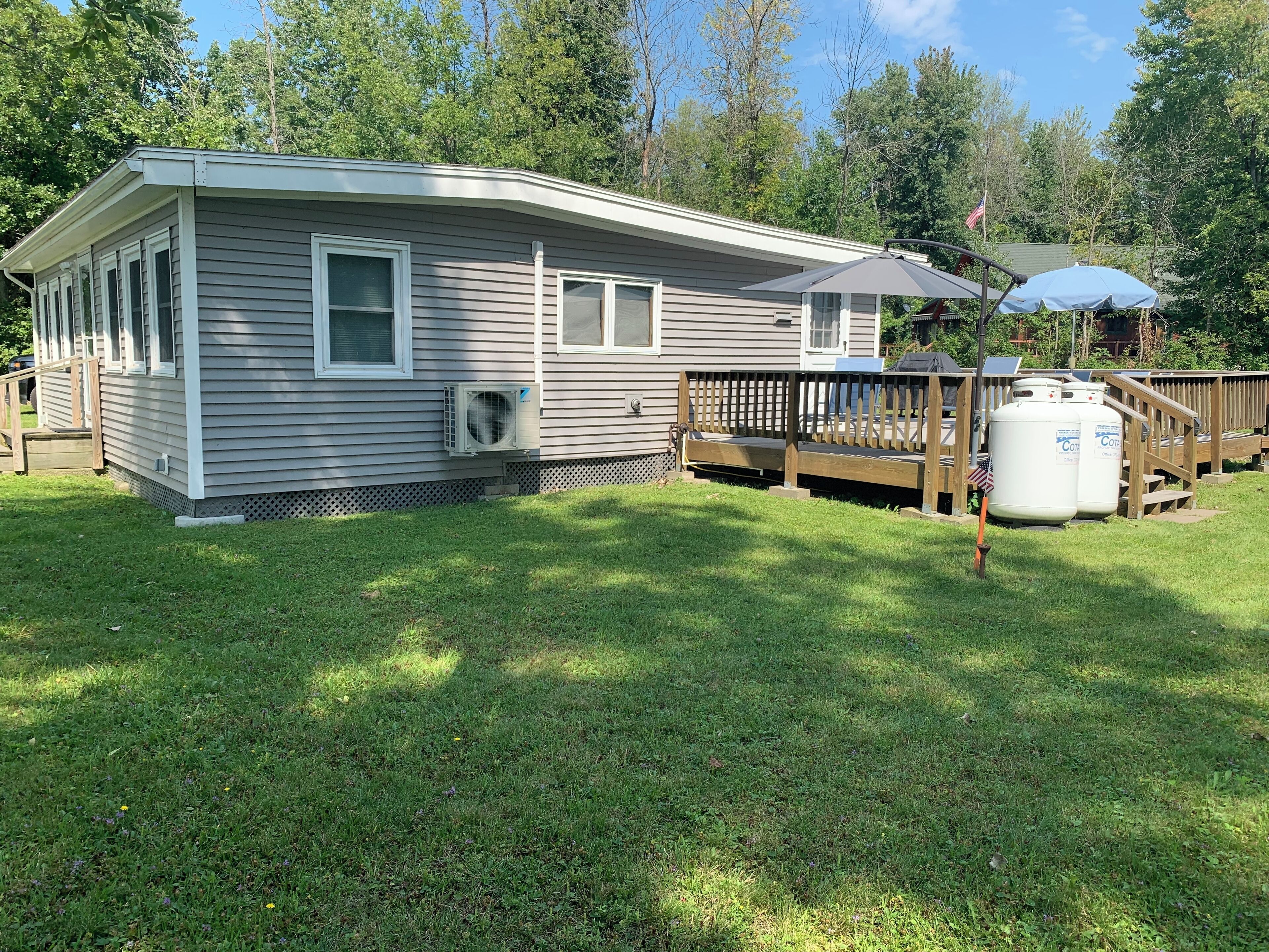 A single-story house with a covered porch, a fenced yard, and a large propane tank.
