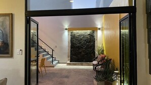 A modern interior with a staircase leading to a second floor, a stone wall, and a seating area with plants.