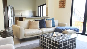 A modern living room with a sofa, a coffee table, and a kitchen in the background.