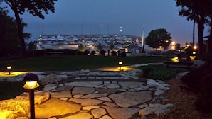 A stone pathway with a lamp post in the foreground, leading to a marina with boats and a distant view of a town. -  Larsen Lodge Downtown Village Egg Harbor, Sauna, New, Rustic and Elegant. (Egg Harbor)
