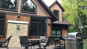 A deck with outdoor furniture, a grill, and a stone wall. -  Larsen Lodge Downtown Village Egg Harbor, Sauna, New, Rustic and Elegant. (Egg Harbor)