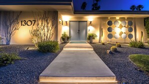 Une maison moderne, portant le numéro 1307, avec un chemin d’accès en béton et un mur décoratif orné de motifs circulaires.