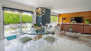 Un espace de salle à manger moderne, avec une table en verre, des chaises transparentes et un luminaire au plafond au design original.