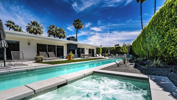 Un espace piscine moderne doté d’un jacuzzi, de chaises longues et d’un jardin bien entretenu.