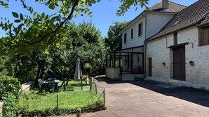 A stone building with a covered patio, a fenced garden, and a clear blue sky. - Listed country house in Périgord between Sarlat, Lascaux and Rocamadour (Salignac-Eyvigues)