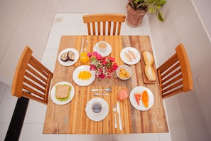 Una mesa de madera con platos de comida, una taza de café y un centro de mesa con flores.