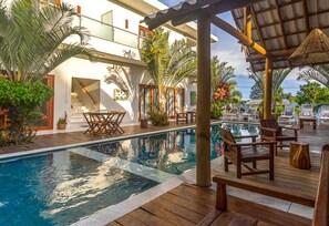 Ein Poolbereich mit Holzterrasse, Liegestühlen und Kübelpflanzen.
