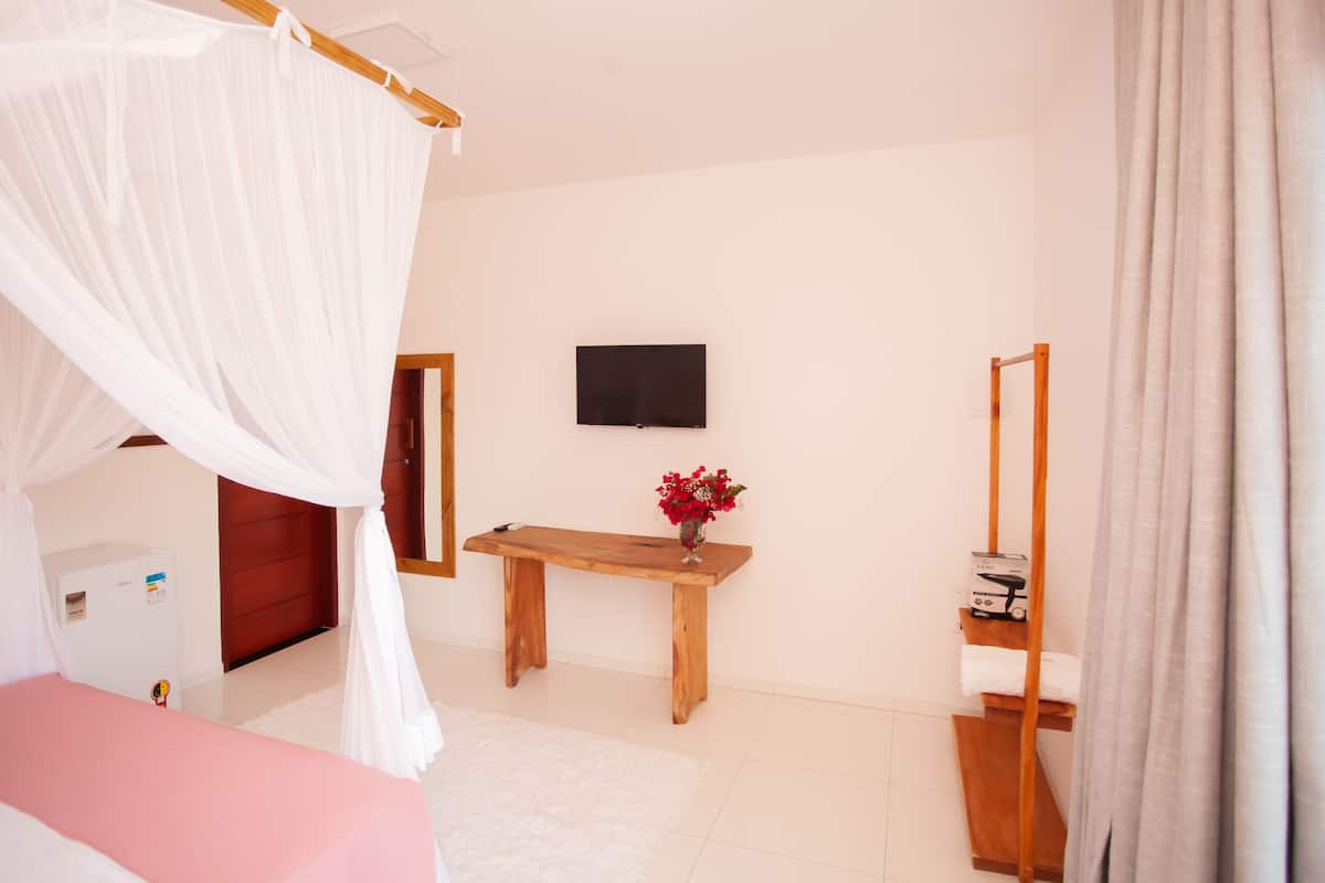 Un dormitorio con cama, mesita de noche, televisión, espejo y armario.