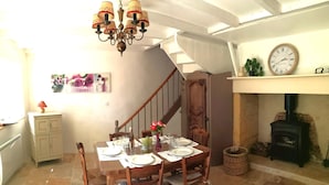 A dining area with a wooden table set for four, a chandelier, a clock, and a fireplace.