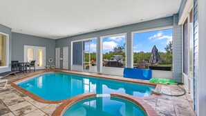 Une piscine bordée de briques, de grandes fenêtres et des meubles d’extérieur.