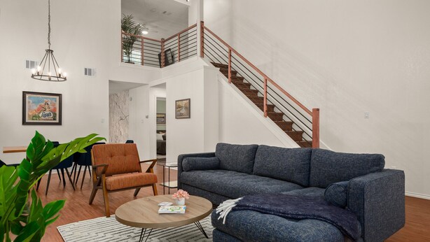Ein modernes Wohnzimmer mit einem blauen Sofa, einem Holztisch und einer Treppe mit hölzernen Geländern.