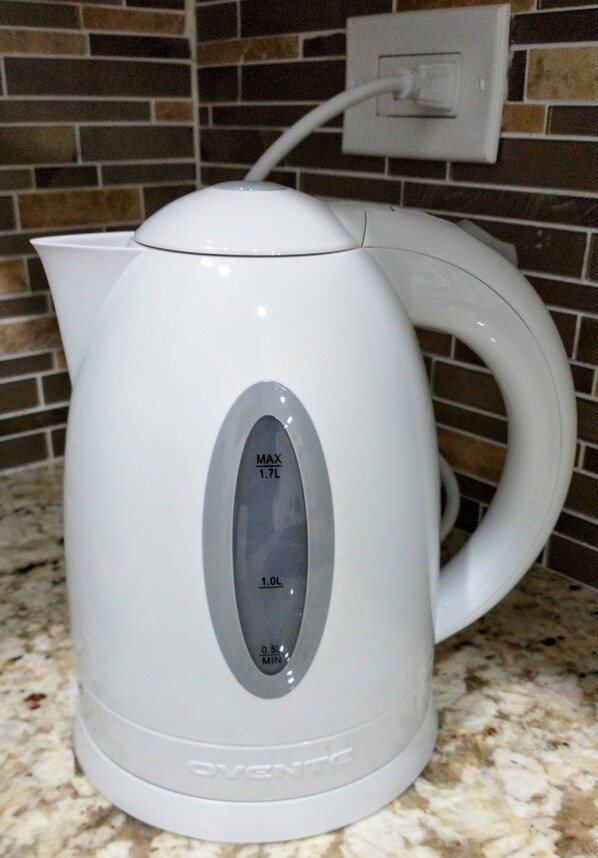 A white electric kettle with a digital display on a granite countertop.