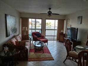 Relax in the spacious living room with a sofa, armchair, and dining table, offering a view of the water and surrounding buildings.