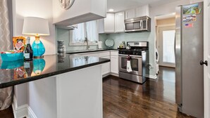 Een moderne keuken met witte kastjes, roestvrijstalen apparatuur en een zwart granieten aanrecht.