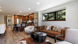 A modern living room with a sofa, chairs, a coffee table, and a dining area with chairs. - Modern Condo in Avon, Walk to BC Gondola, SA228 (Avon)