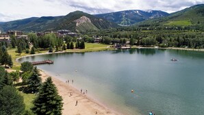 A lakeside resort with a sandy beach, a dock, and a view of mountains in the background. - Modern Condo in Avon, Walk to BC Gondola, SA228 (Avon)