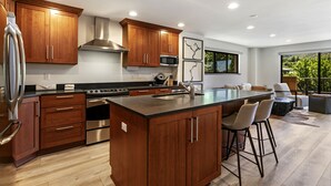 A modern kitchen with wooden cabinets, stainless steel appliances, and a large island with bar stools. - Modern Condo in Avon, Walk to BC Gondola, SA228 (Avon)
