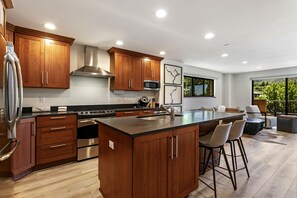 A modern kitchen with wooden cabinets, stainless steel appliances, and a large island with bar stools.