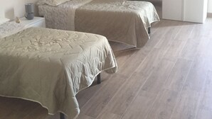 A bedroom with two beds, a wardrobe, and a bedside table.