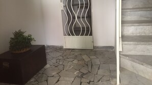 A stone-tiled floor, a white radiator, and a staircase with a metal railing.