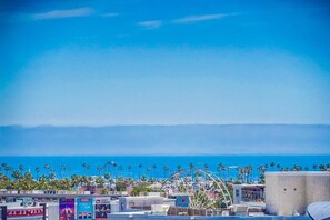 A coastal cityscape with a clear view of the ocean, palm trees, and a Ferris wheel. - Ocean View Getaway! (Long Beach)