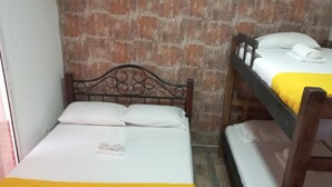 A room with two beds, one with a yellow bedspread and the other with white bedding.