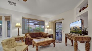 A living room with a sofa, armchair, coffee table, and TV stand.