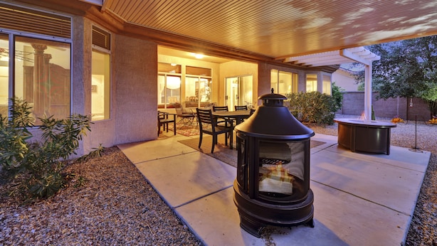 An outdoor patio area with a wood-burning stove, a dining table with chairs, and a covered seating area.