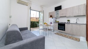 A modern kitchen with white cabinets, a built-in oven, and a dining area with a table and chairs. - Sottovoce app.to vicino al mare (Piano di Sorrento)