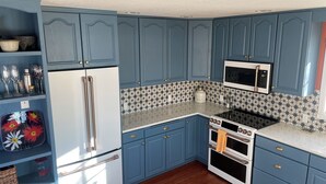 Una cocina con gabinetes azules, un refrigerador blanco, un microondas y una estufa.