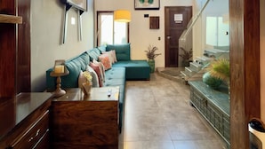A spacious living room with a sectional sofa, a wooden coffee table, and a staircase leading to an upper level.