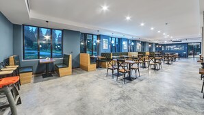 A spacious indoor area with multiple seating arrangements, including tables and booths, and large windows providing views of the outdoors. - Mountain Resort Gantiadi (Borjomi)