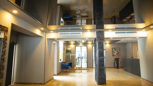 A spacious lobby with a high ceiling, a central pillar, and a seating area with a blue chair. - Mountain Resort Gantiadi (Borjomi)