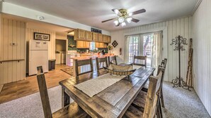 A spacious kitchen with wooden cabinets, a dining table with chairs, and a ceiling fan.