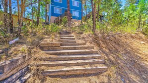 A multi-story building with a blue exterior, surrounded by trees and a wooden staircase leading to the entrance.
