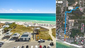 Strandudsigt med parkeringsplads, adgang til stranden og en træpromenade der fører til stranden.