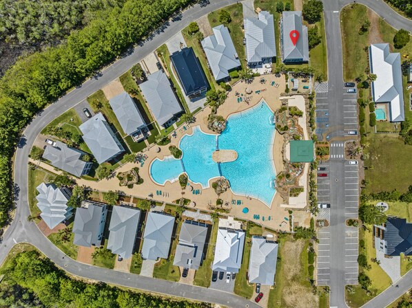 Vista aèria d'una zona residencial amb una gran piscina, diverses cases i un aparcament.