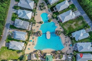Vista aèria d'un complex turístic amb una piscina central, diverses viles i un paisatge ben cuidat.