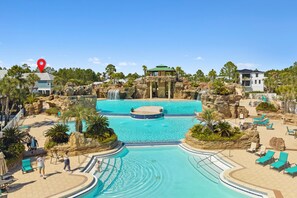 Un complex turístic amb una gran piscina, cascada i zona de relaxació.