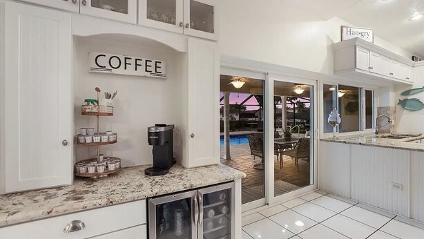 Et moderne køkken med kaffestation, et skilt med teksten "COFFEE" og udsigt til et udendørs poolområde.