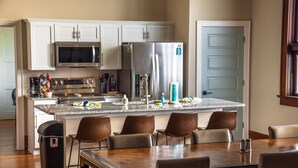 A modern kitchen with white cabinets, stainless steel appliances, and a central island with chairs. - Dragonfly Inn (Only 40 min to Hocking Hills area) (Amanda)