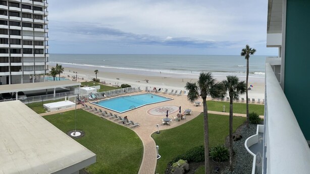 A hotel with a pool, beach view, and palm trees. - Beach front home away from home (Daytona Beach)