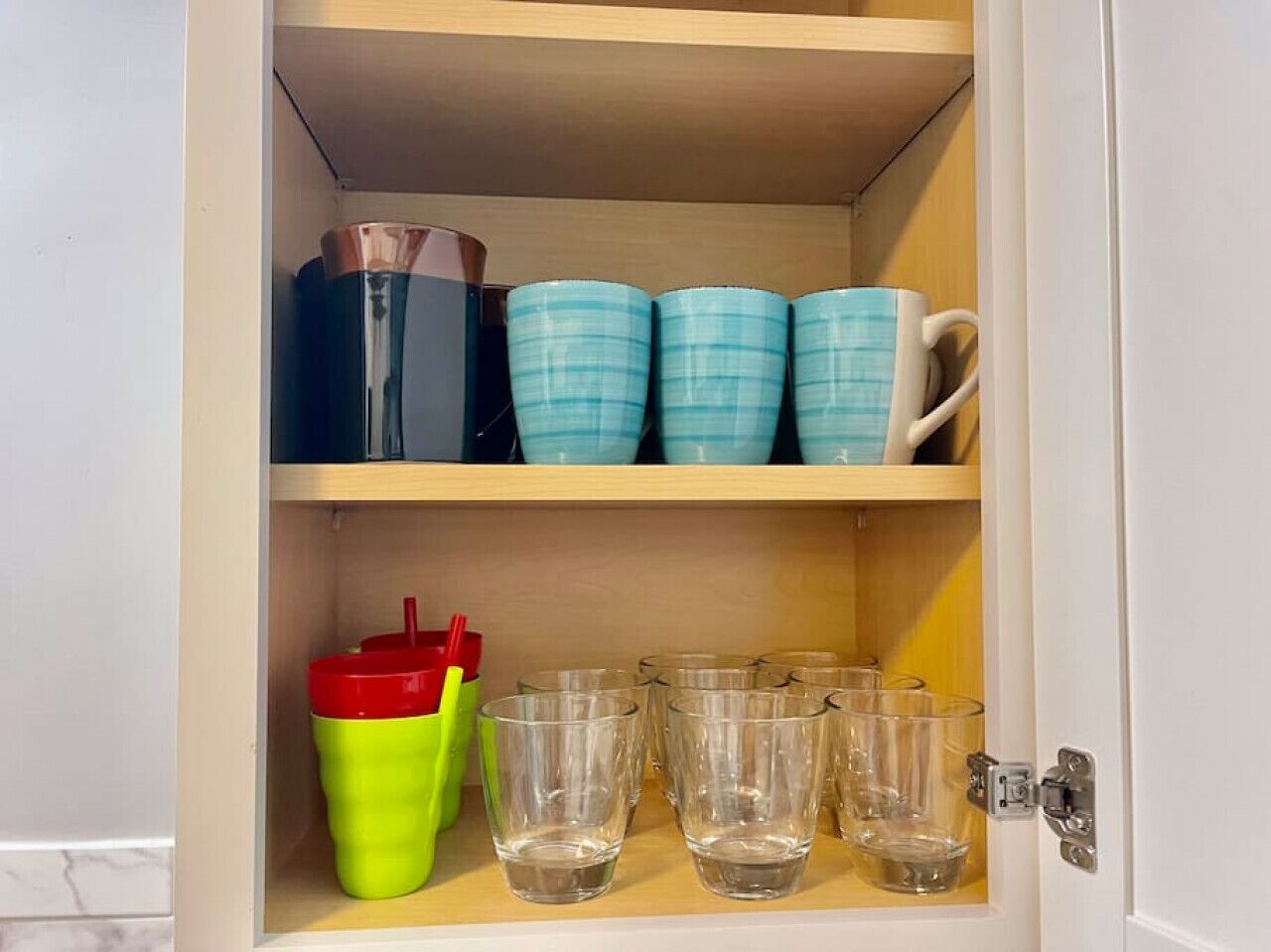 A cabinet with shelves containing various glassware and containers.