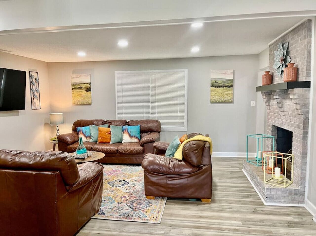 A living room with a fireplace, leather sofas, a coffee table, and a patterned rug.