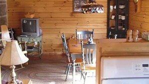 Een houten chalet inrichting met een eethoek, een televisie en een koelkast.