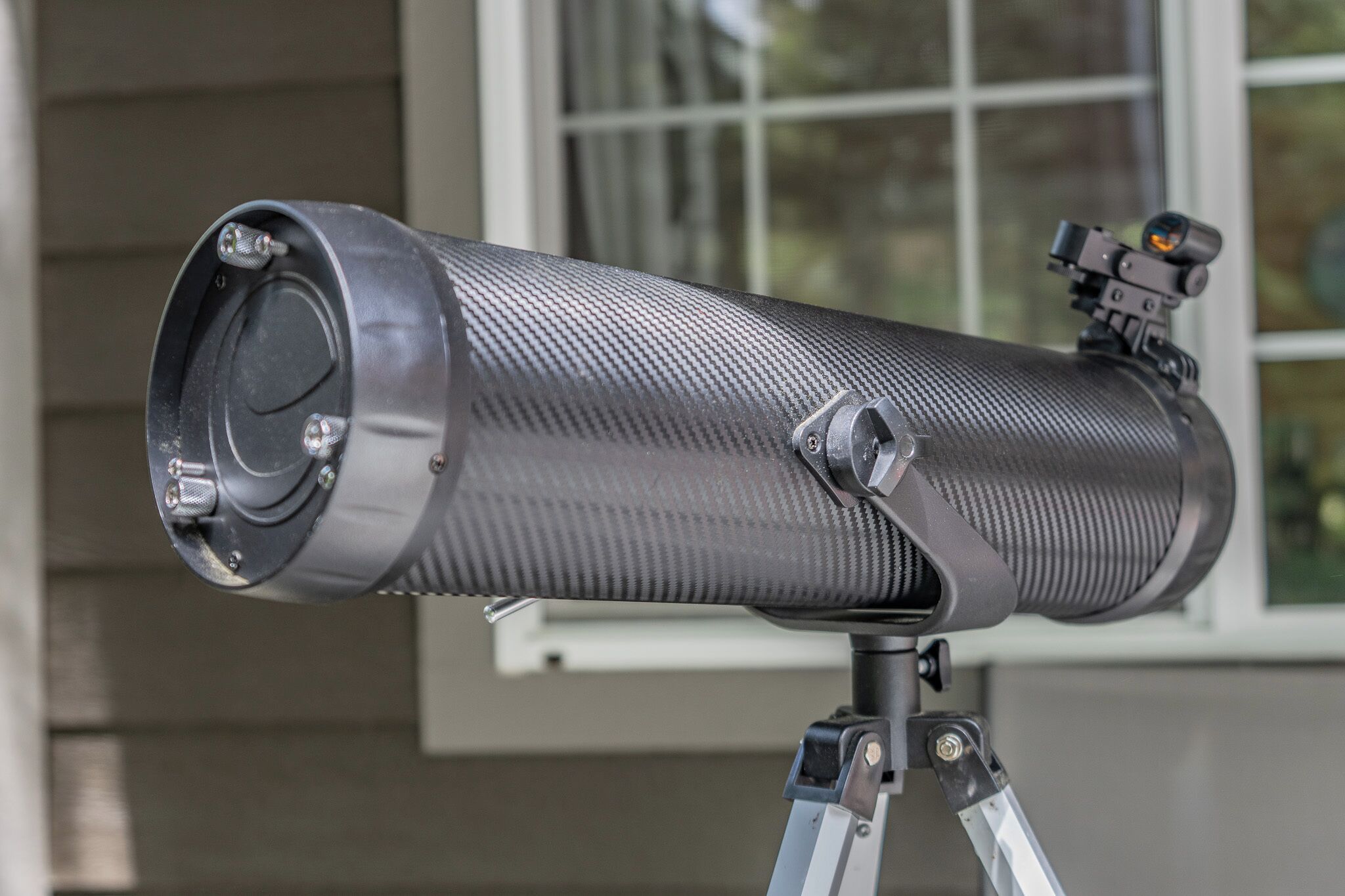 Un telescopio sobre un trípode con una ventana al fondo.