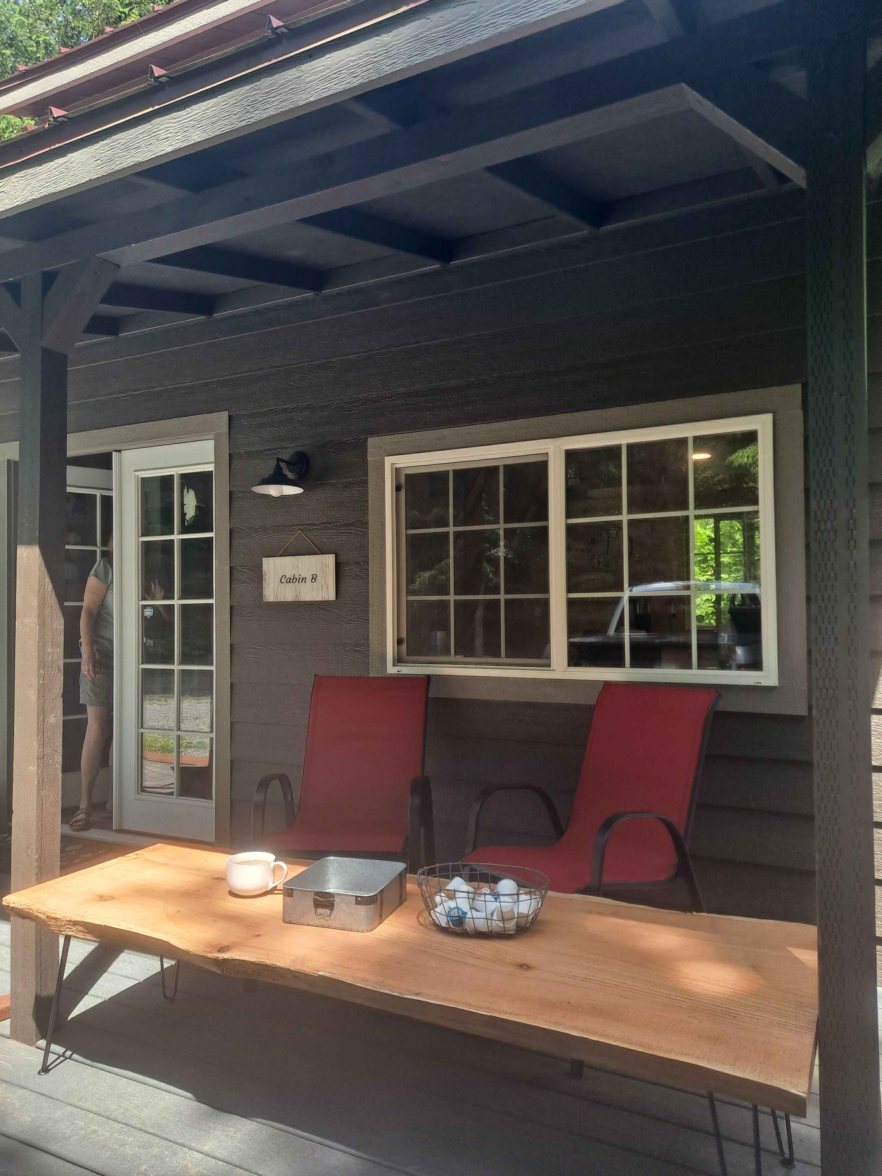 Een houten terras met een tafel, stoelen en een bordje met de tekst 'Cabin B'.