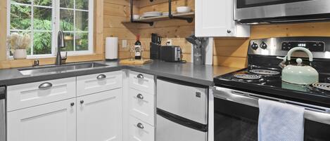 Una cocina moderna con gabinetes blancos, una estufa de acero inoxidable y un microondas.
